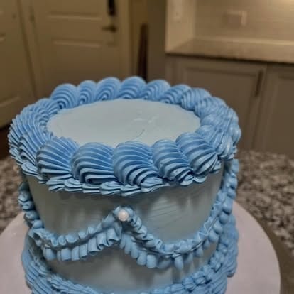 Blue frosted baby shower cake with piped details