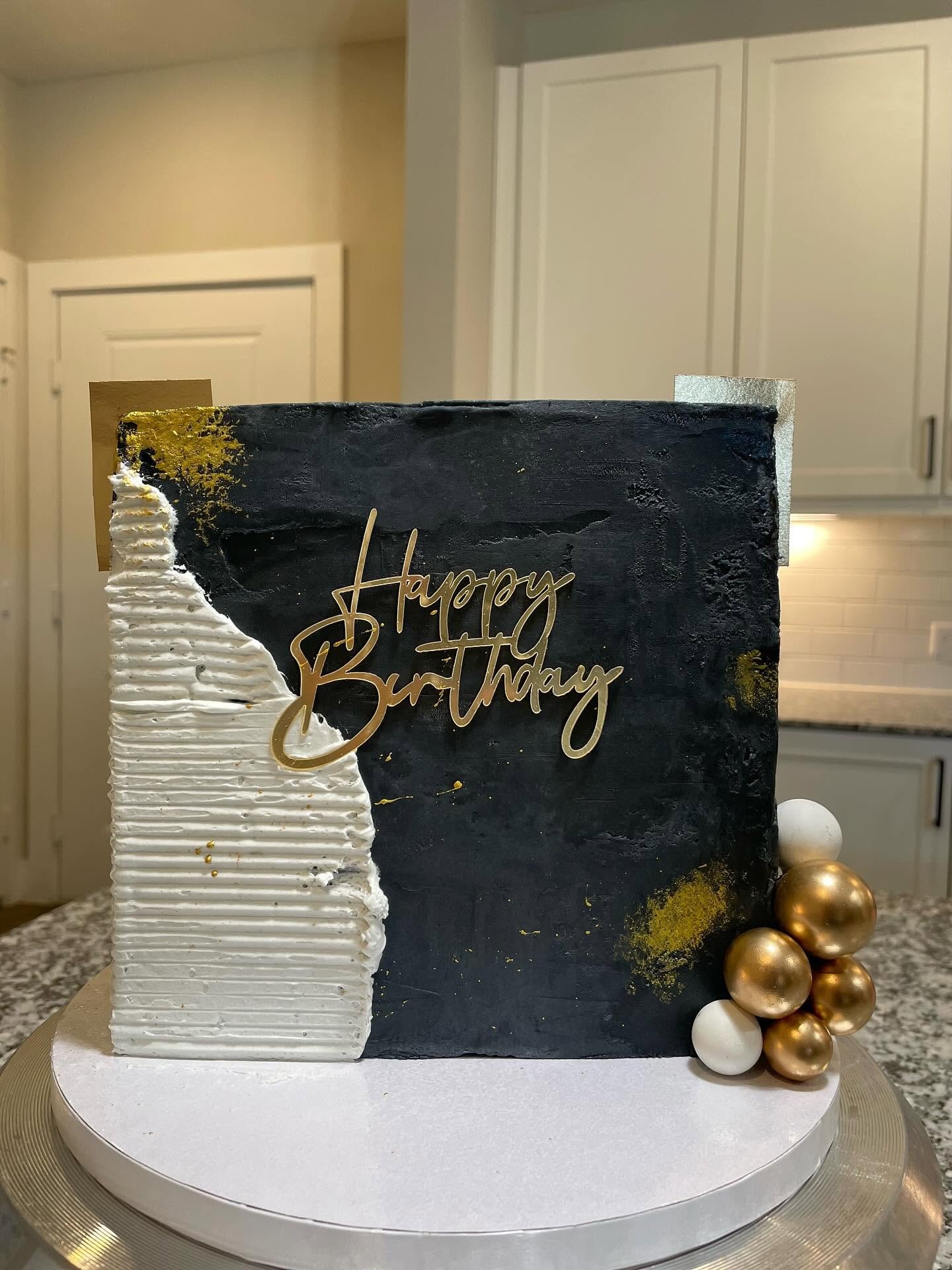 Black and gold textured birthday cake with Happy Birthday topper