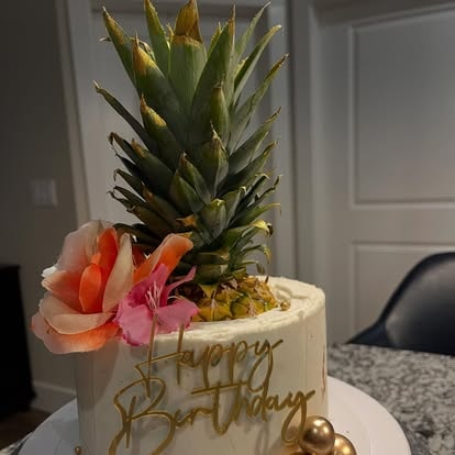 Pineapple topped birthday cake with fresh flowers and gold lettering