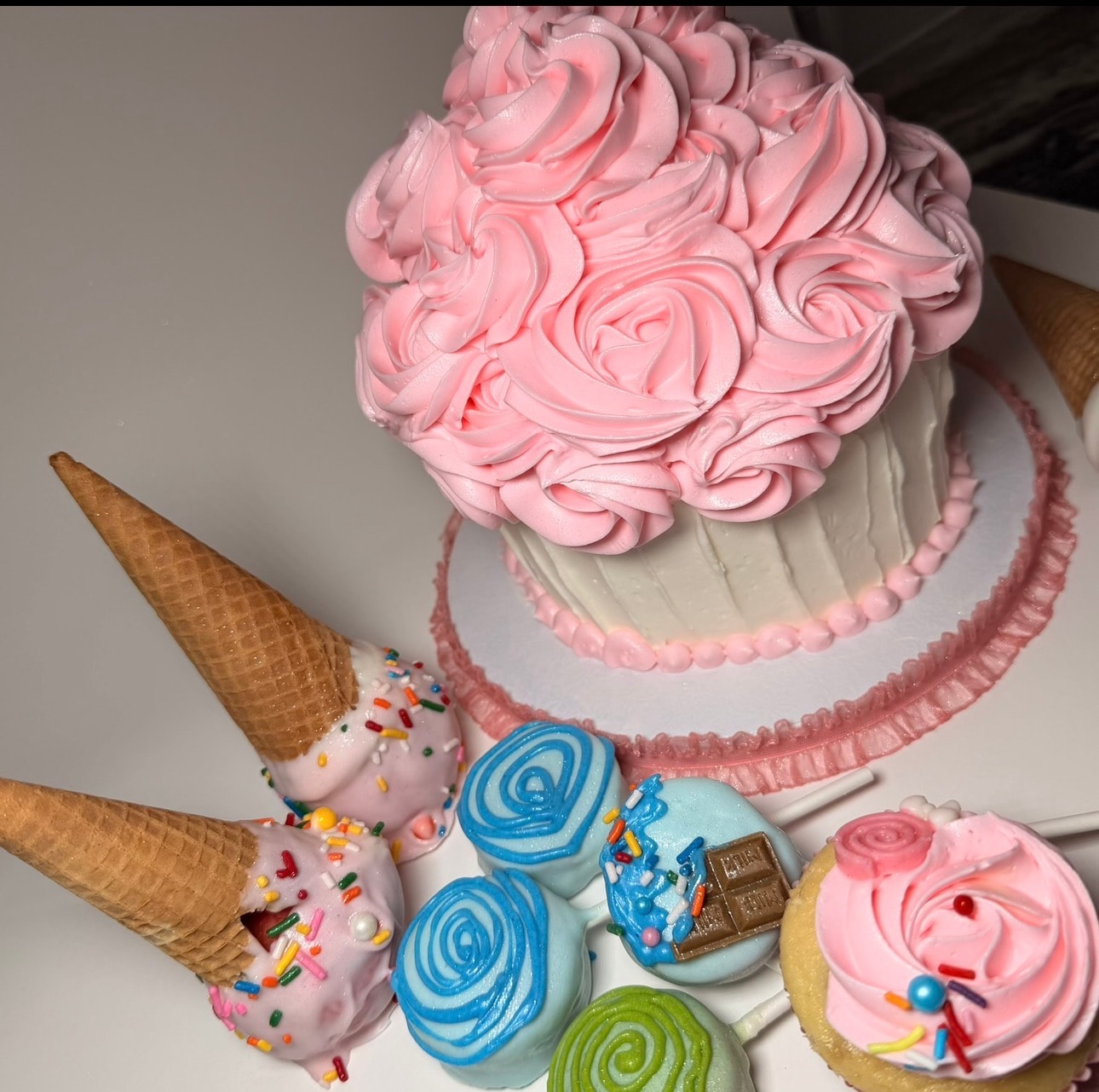 Giant cupcake cake with pink rosette frosting and treats display