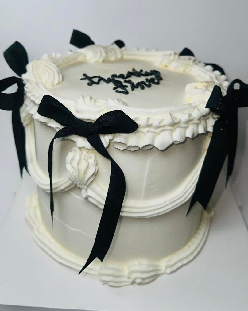 Elegant white birthday cake with black ribbon bows