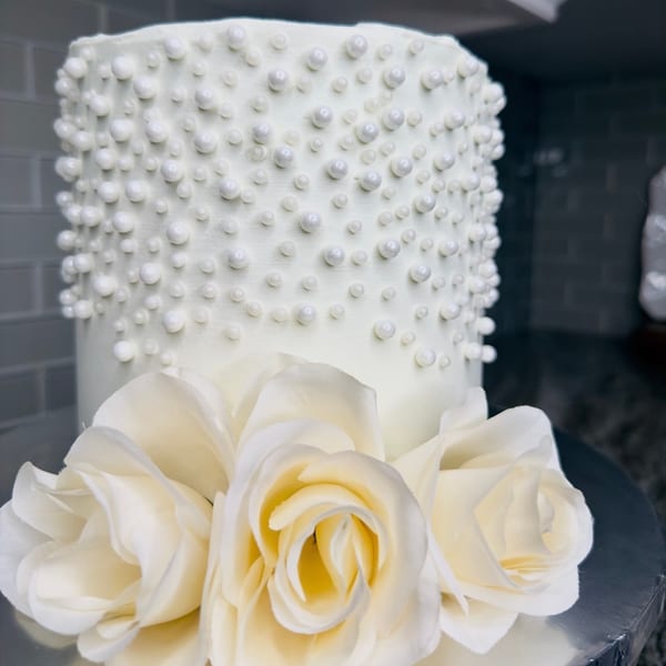 White wedding cake with pearl beads and roses
